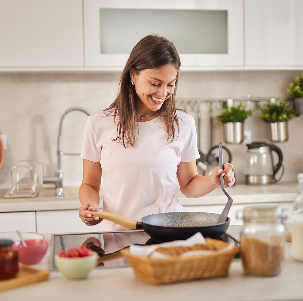 Woman cooking in a modern kitchen, smiling.
