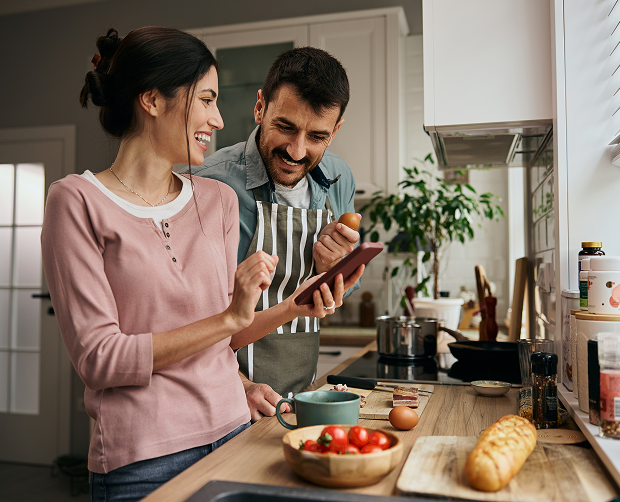 Couple cooking together while using a tablet.