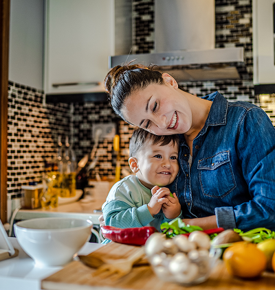 Smiling mother and child in kitchen cooking.