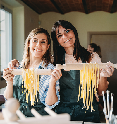 Two women holding homemade pasta together.
