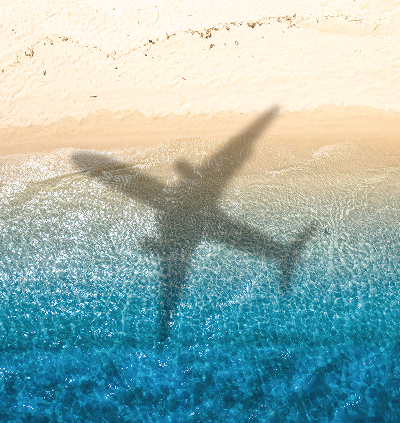 Airplane shadow over beach and ocean waves.
